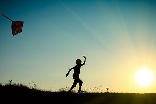 lapsi juoksee auringonlaskussa